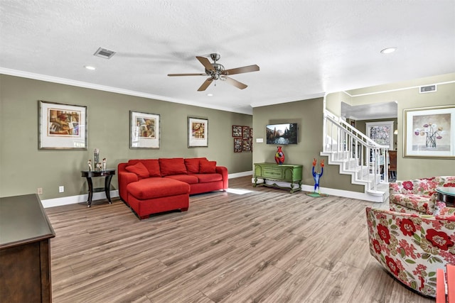 living room featuring crown molding, light hardwood / wood-style floors, a textured ceiling, and ceiling fan