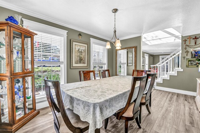 dining room with light hardwood / wood-style flooring, ornamental molding, an inviting chandelier, and a textured ceiling