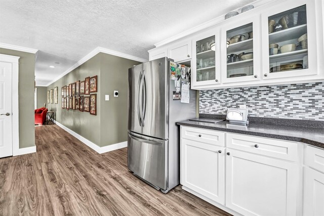 kitchen with white cabinetry, crown molding, decorative backsplash, and stainless steel fridge