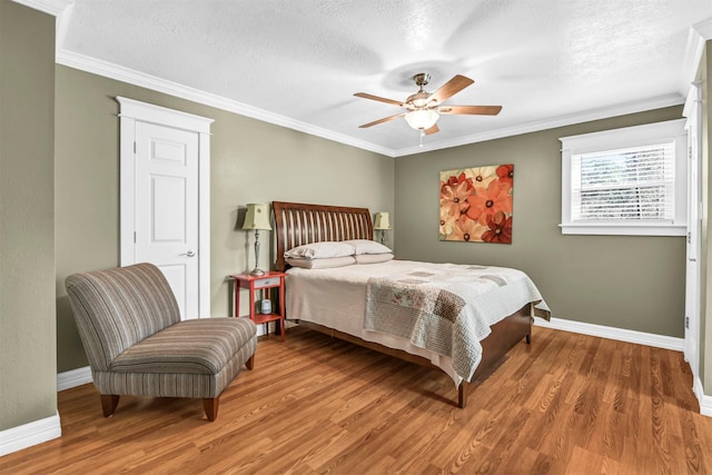 bedroom featuring ceiling fan, a textured ceiling, hardwood / wood-style flooring, and crown molding