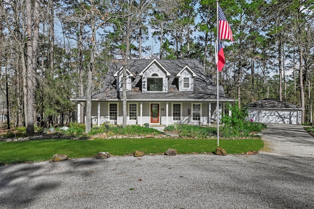 new england style home with concrete driveway, an outbuilding, covered porch, a detached garage, and a front yard
