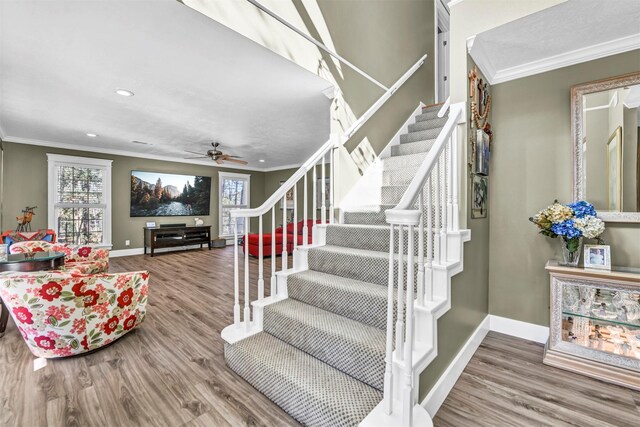 stairway with hardwood / wood-style flooring, ceiling fan, and ornamental molding