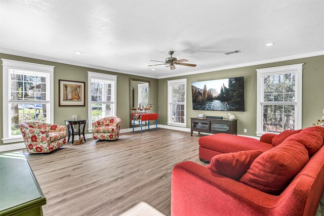 living room featuring crown molding, light hardwood / wood-style floors, ceiling fan, and plenty of natural light