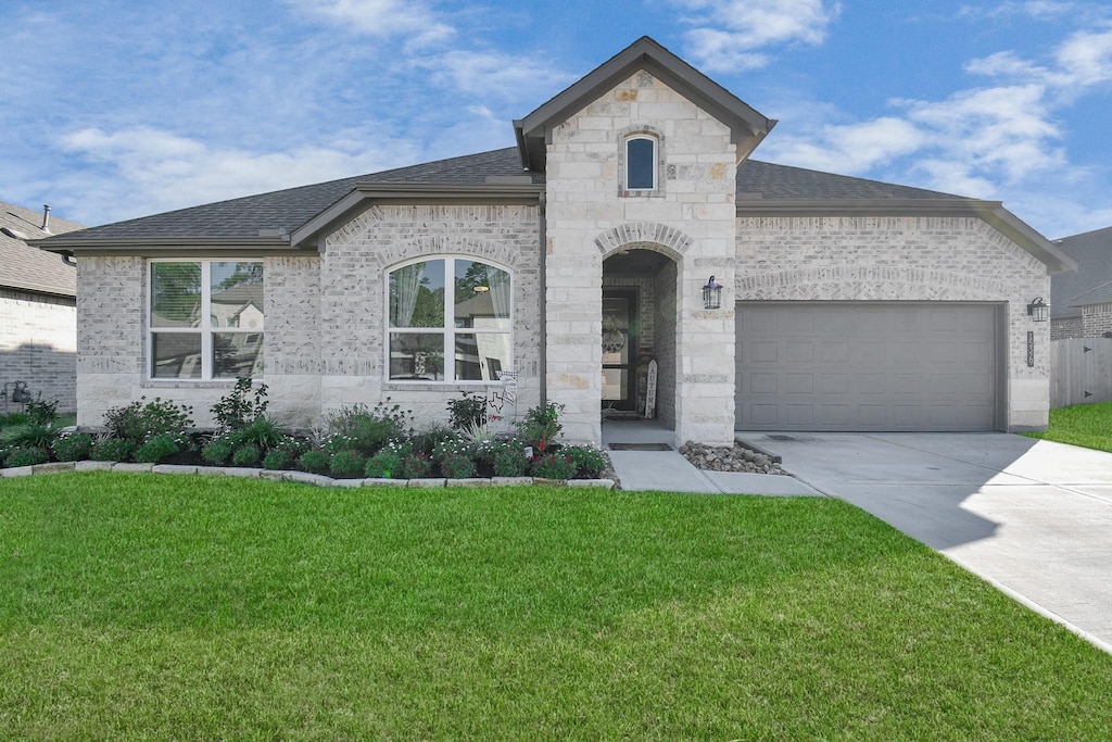 french country inspired facade featuring a garage and a front yard