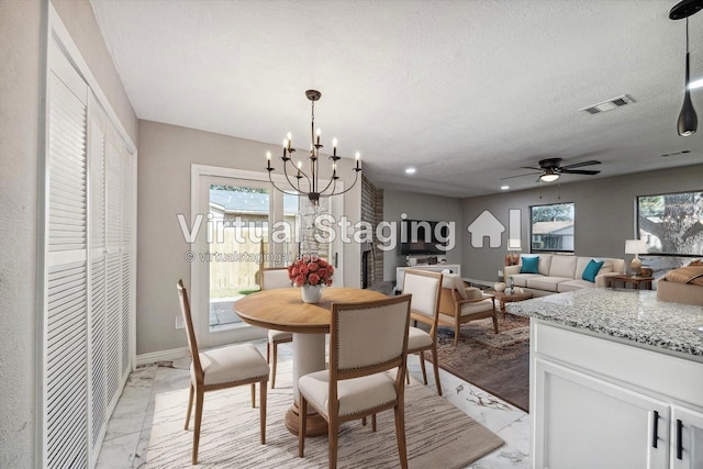 dining room featuring ceiling fan with notable chandelier and a textured ceiling