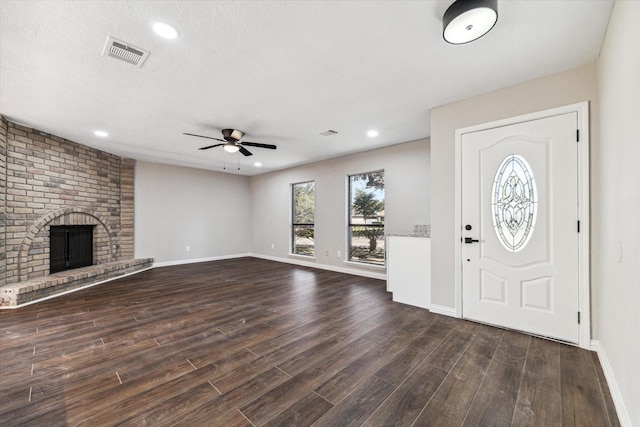 entryway with a textured ceiling, ceiling fan, dark hardwood / wood-style flooring, and a fireplace