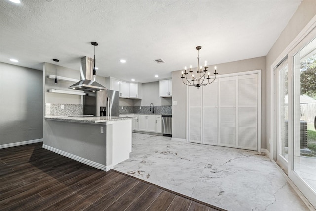 kitchen with island exhaust hood, kitchen peninsula, stainless steel appliances, decorative light fixtures, and white cabinetry