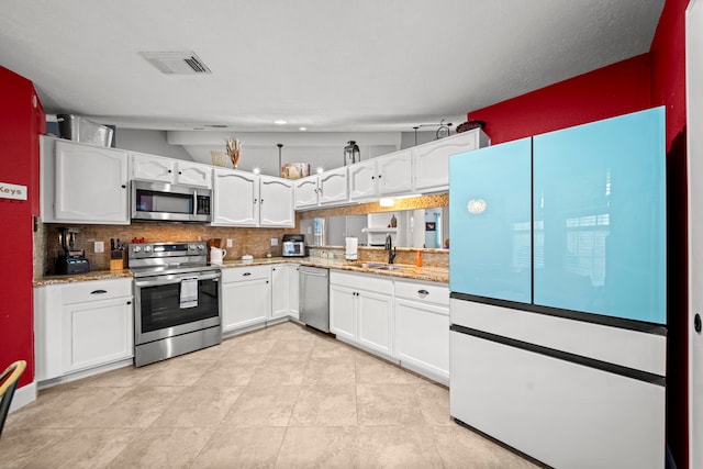 kitchen with stainless steel appliances, white cabinetry, sink, and backsplash