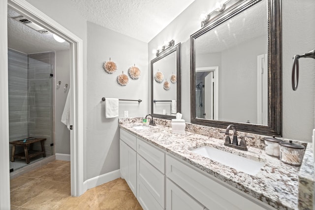 bathroom with vanity, a shower with shower door, tile patterned flooring, and a textured ceiling