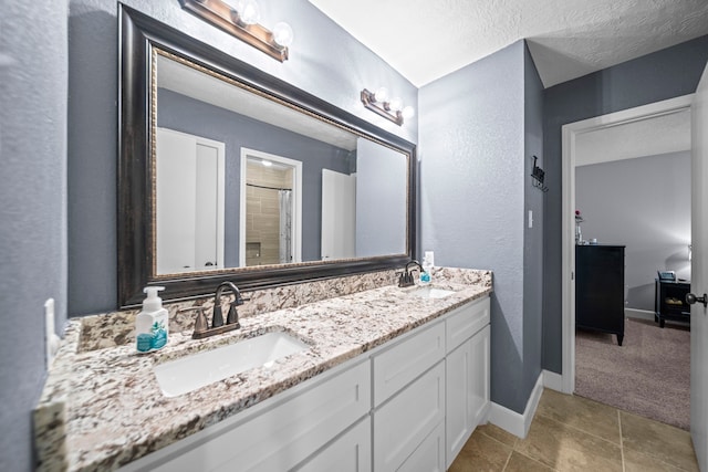 bathroom featuring vanity, a shower, and a textured ceiling