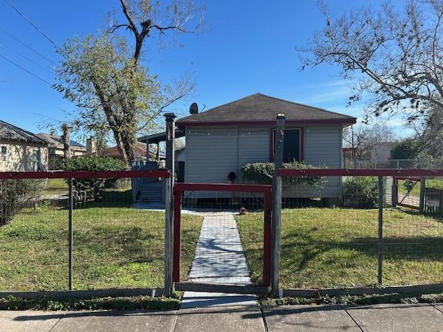 view of gate with a fenced front yard and a lawn