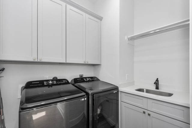 laundry room featuring sink, washer and clothes dryer, and cabinets