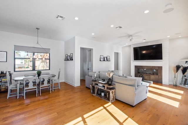 living room with a fireplace, light hardwood / wood-style floors, and ceiling fan