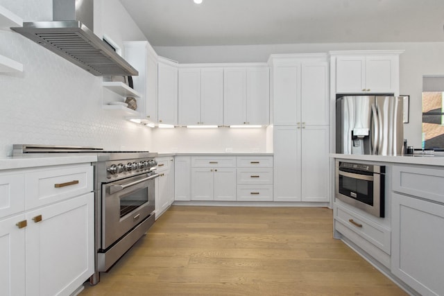 kitchen featuring stainless steel appliances, white cabinetry, exhaust hood, and light hardwood / wood-style flooring