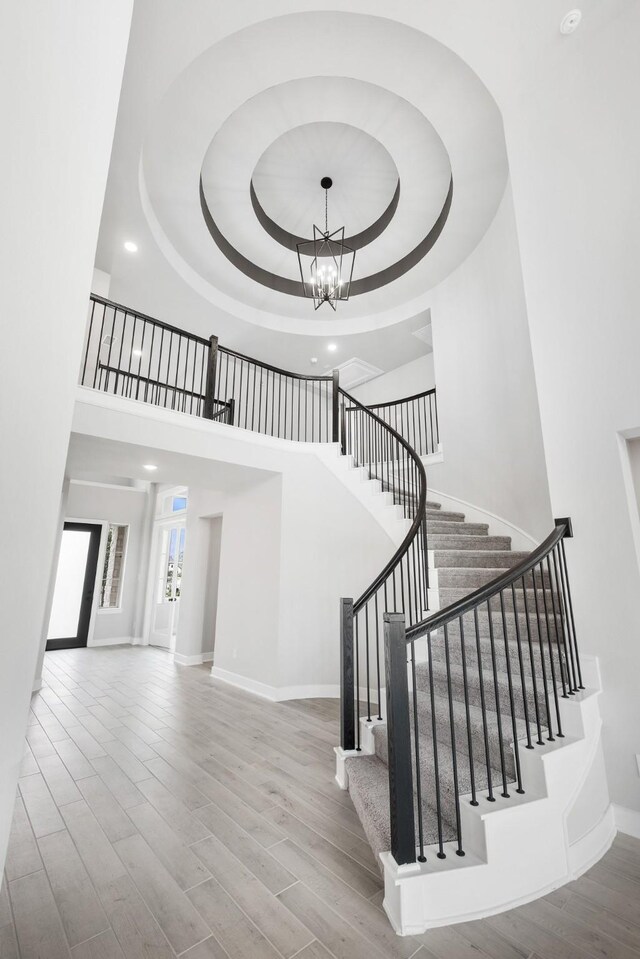 stairs featuring a tray ceiling, a towering ceiling, and a chandelier