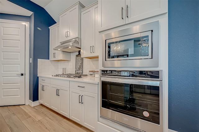 kitchen with appliances with stainless steel finishes, backsplash, light hardwood / wood-style flooring, and white cabinetry