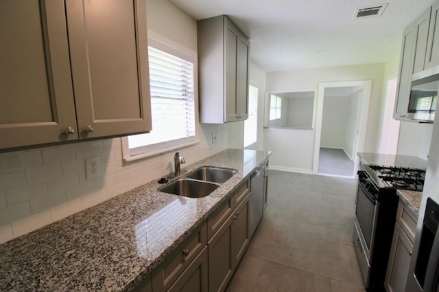 kitchen with light stone counters, sink, appliances with stainless steel finishes, and tasteful backsplash