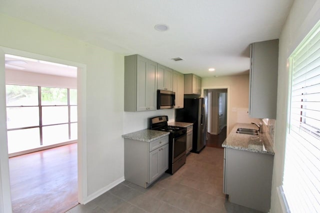 kitchen with appliances with stainless steel finishes, light stone counters, and sink