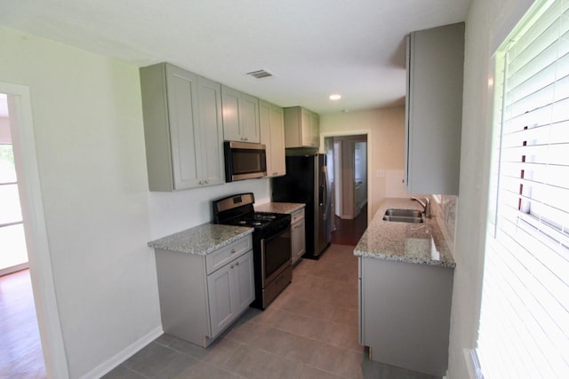 kitchen featuring tile patterned floors, light stone countertops, sink, and appliances with stainless steel finishes