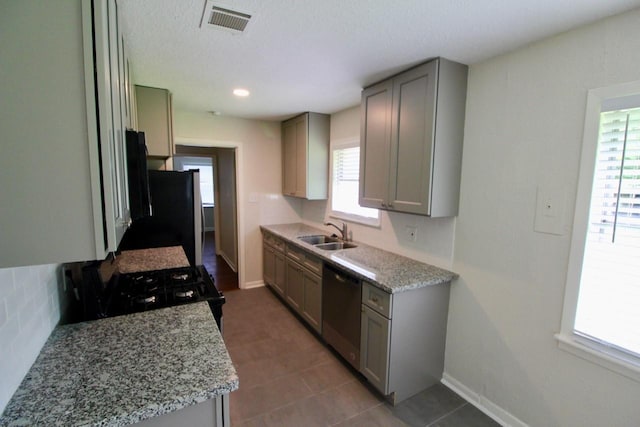 kitchen with light stone countertops, sink, dishwasher, gray cabinets, and fridge