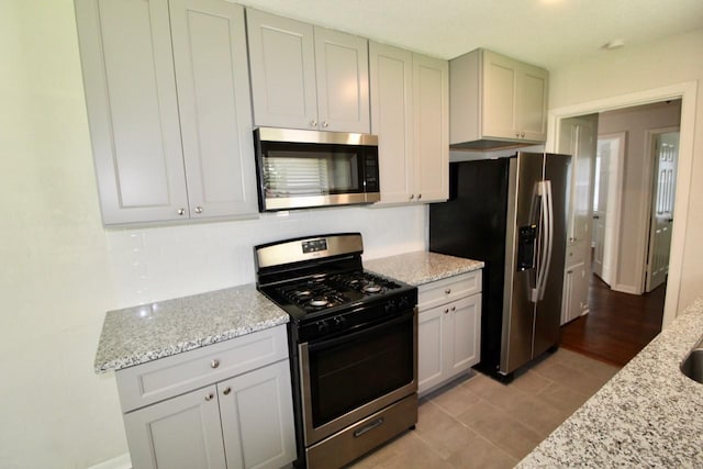 kitchen with light stone countertops and appliances with stainless steel finishes