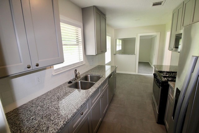 kitchen featuring light stone counters, sink, and appliances with stainless steel finishes