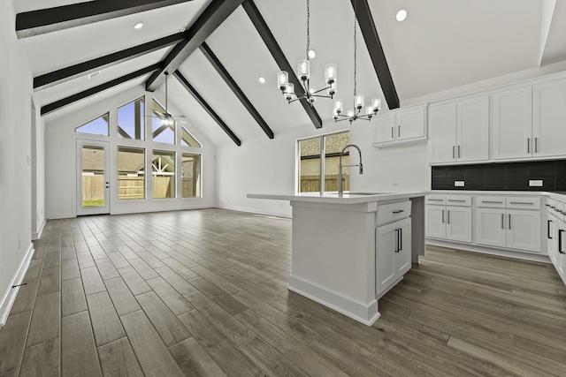 16710 Yaklin Meadow Ct, Humble, TX 77346 - kitchen featuring a chandelier, beamed ceiling, open floor plan, backsplash, and white cabinetry