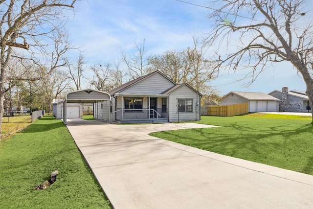 single story home with a garage, a front lawn, covered porch, a carport, and an outbuilding