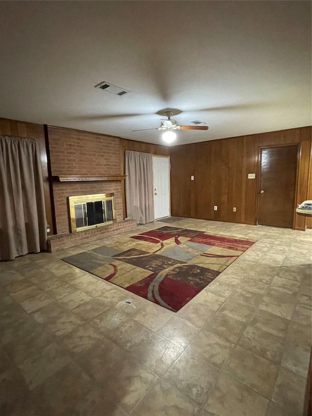 living room with ceiling fan, wooden walls, and a brick fireplace