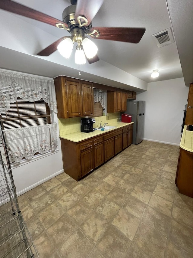 kitchen with stainless steel refrigerator, ceiling fan, sink, and decorative backsplash