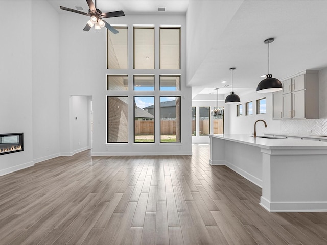 3248 Stingray Cove Dr, Katy, TX 77493 - unfurnished living room with wood finished floors, a ceiling fan, a sink, baseboards, and a glass covered fireplace