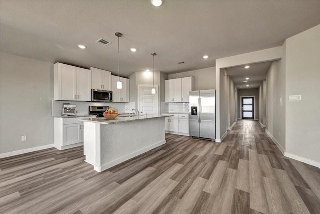 kitchen with white cabinets, pendant lighting, stainless steel appliances, and tasteful backsplash