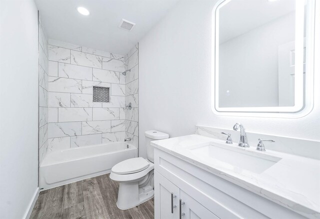 full bathroom with hardwood / wood-style floors, vanity, toilet, and tiled shower / bath