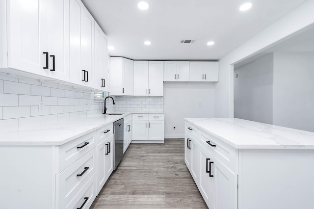 kitchen with light stone countertops, dishwasher, sink, light hardwood / wood-style flooring, and white cabinets