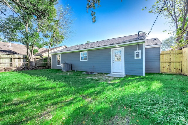 rear view of property with a yard and central air condition unit