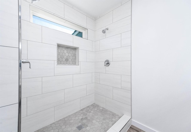 bathroom with tiled shower and hardwood / wood-style flooring