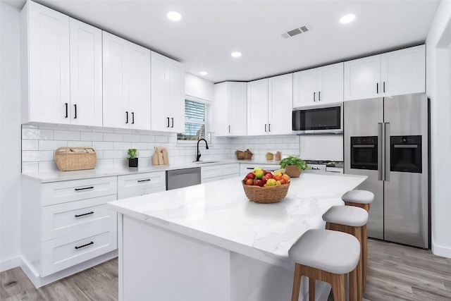 kitchen with white cabinets, stainless steel appliances, and a kitchen island