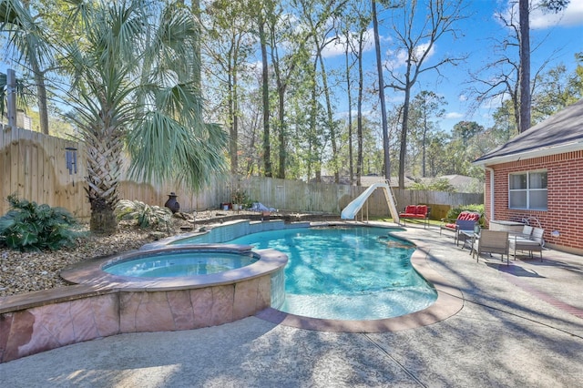 view of pool with an in ground hot tub, a patio area, and a water slide