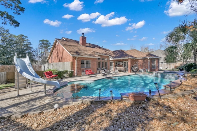 view of swimming pool with a water slide and a patio