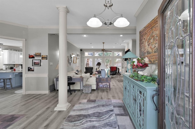 foyer featuring decorative columns, light hardwood / wood-style floors, ceiling fan with notable chandelier, and ornamental molding