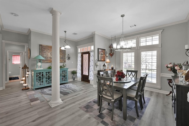 dining space featuring wood-type flooring, ornate columns, and crown molding