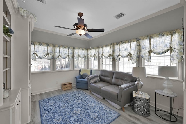 living room with light hardwood / wood-style flooring, ceiling fan, and ornamental molding