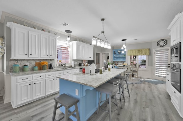 kitchen with a center island, white cabinets, oven, decorative backsplash, and ornamental molding