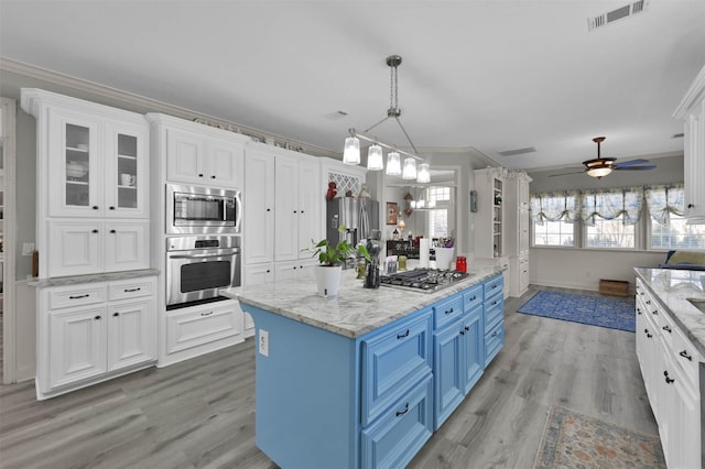 kitchen with blue cabinetry, white cabinetry, a center island, stainless steel appliances, and crown molding