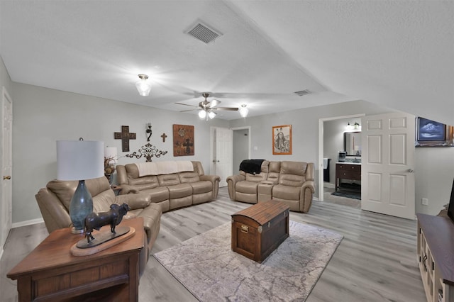 living room with ceiling fan, light hardwood / wood-style floors, and a textured ceiling