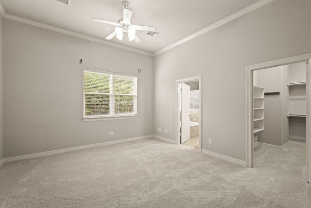 unfurnished bedroom featuring a walk in closet, ceiling fan, ornamental molding, connected bathroom, and light colored carpet