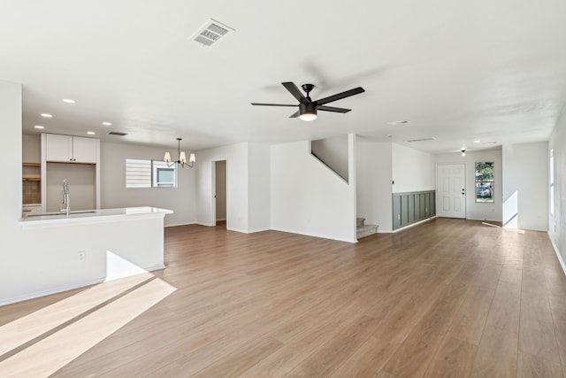 unfurnished living room with ceiling fan with notable chandelier, light hardwood / wood-style flooring, a healthy amount of sunlight, and sink