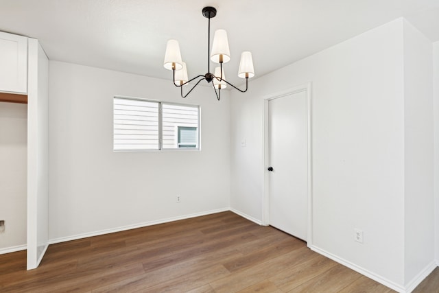 empty room featuring wood-type flooring and an inviting chandelier