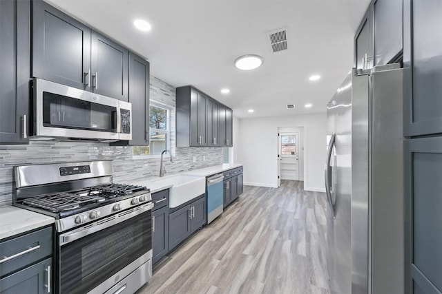 kitchen with stainless steel appliances, sink, plenty of natural light, and light wood-type flooring