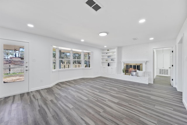 unfurnished living room featuring a fireplace, built in features, and light hardwood / wood-style floors